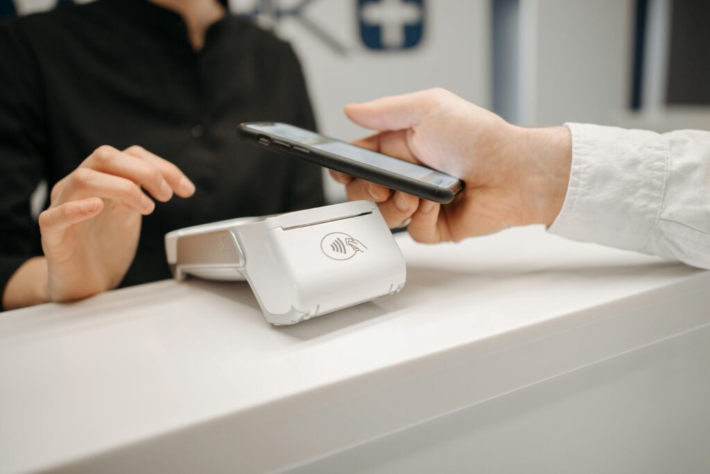pexels-photo-6812431-6812431 Person using a smartphone for contactless payment at a retail counter, highlighting cashless convenience.