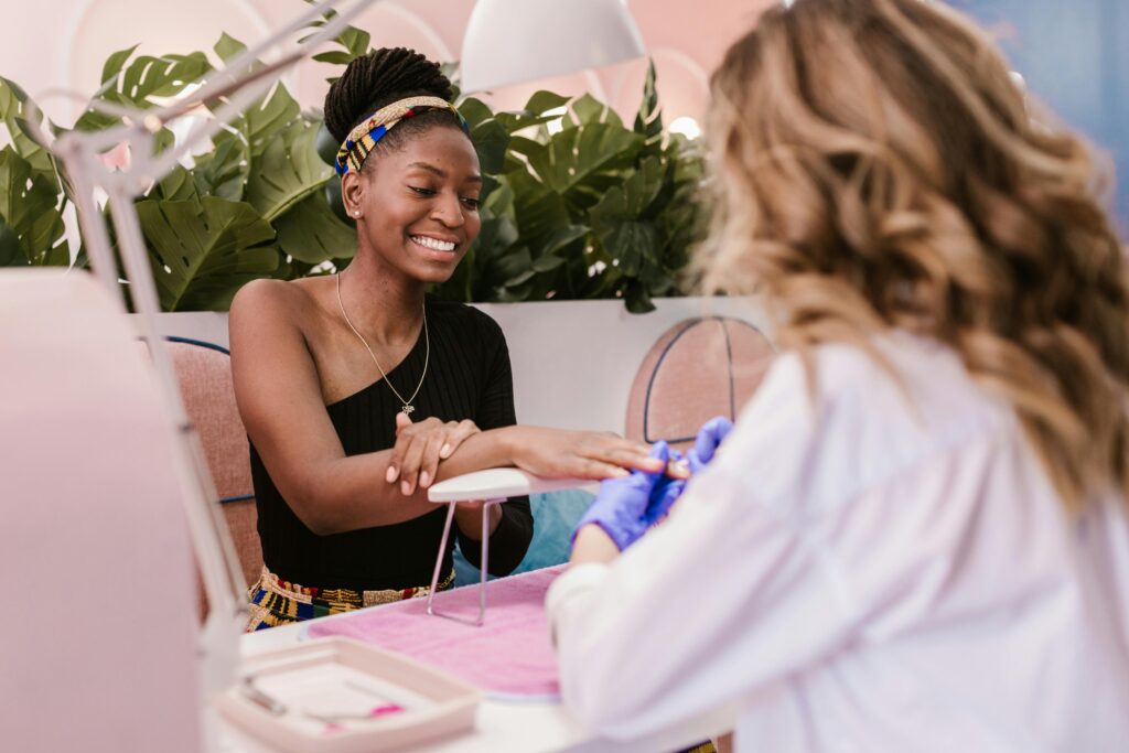 pexels-photo-7755665-7755665 African American woman happily receiving a manicure in a stylish, modern nail salon.